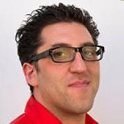 Headshot of a man with dark hair and glasses, who is wearing a red shirt.