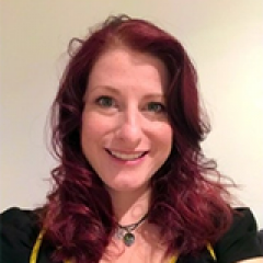 Headshot of a women with dark red hair in front of a white background.